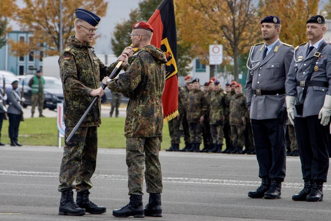 Zwei Soldaten stehen einander gegenüber und halten mit ihren Händen eine Deutschlandfahne