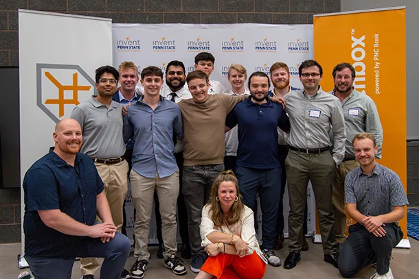 A group of 14 people pose in front of a backdrop