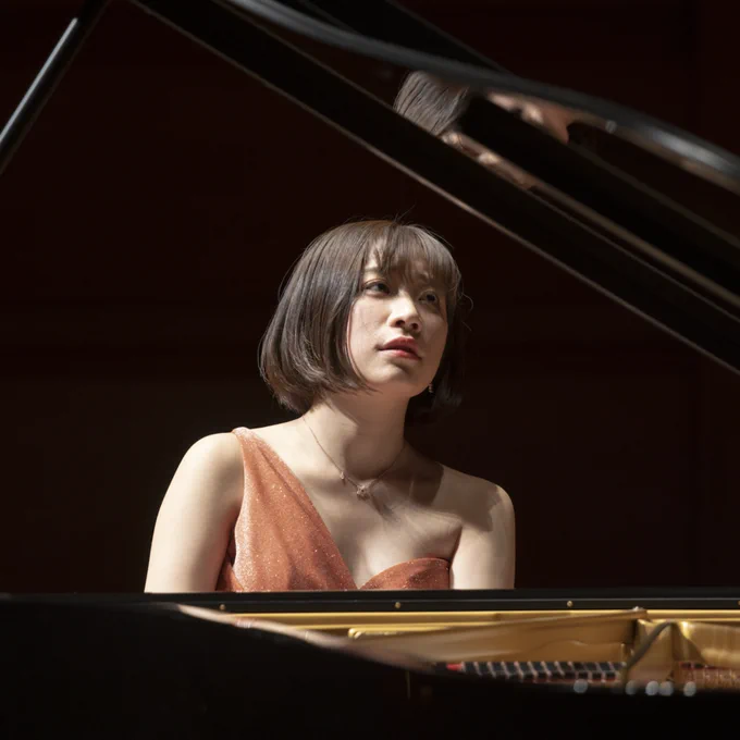 A woman with a bob and bangs plays the piano.