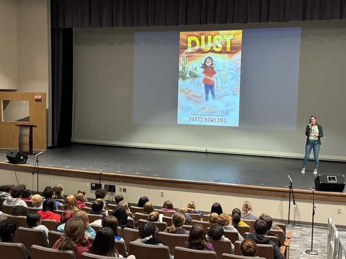 Students in audience listening to woman on stage