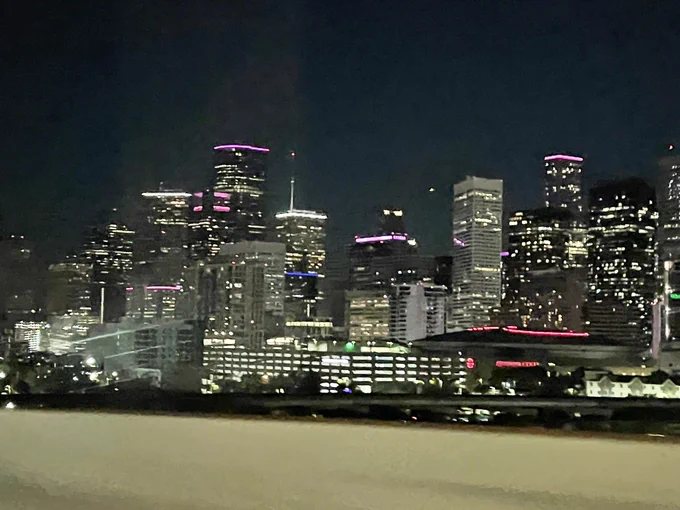 A blurry pic of the downtown Houston skyline at night as seen through the window of an Uber