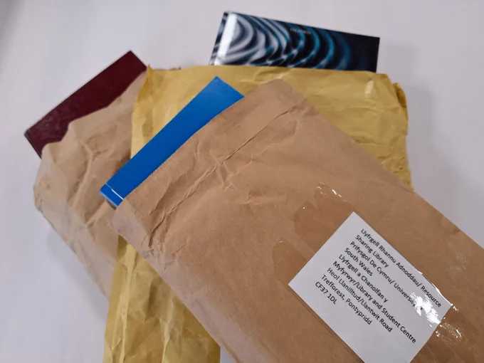 Pentwr o barseli ar fwrdd gwyn / Pile of parcels on white table