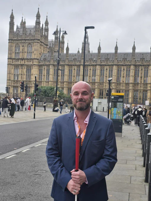 Justin standing in front of Parliament wearing a suit and holding his cane.