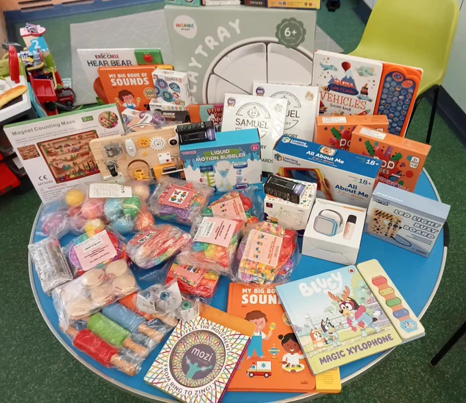 Photo of a variety of children's educational toys and books are displayed on a round blue table, including puzzles, books, and more.