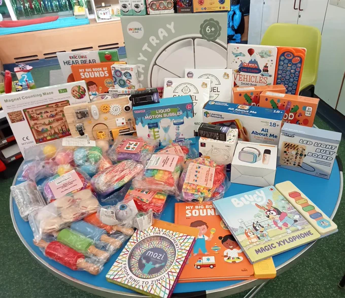 Photo of a variety of children's educational toys and books are displayed on a round blue table, including puzzles, books, and more.