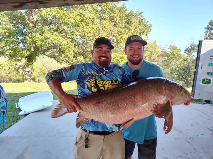 Ryan Young and fishing guide Kris Nelson hold the new state record black buffalo reeled in from Stockton Lake on Oct. 13.