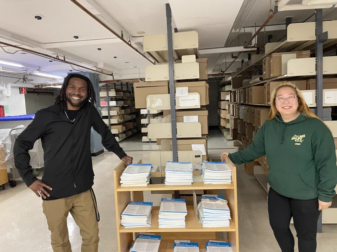 Two LAC employees on either side of a small bookcase.