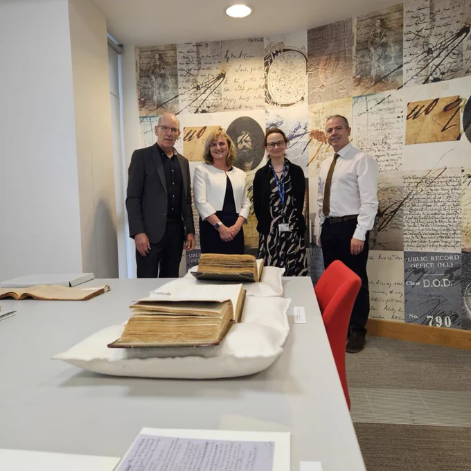 Four individuals standing in the PRONI Reading Room in front of a document display