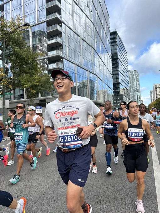 Participants running in the Chicago Marathon with urban buildings in the background.