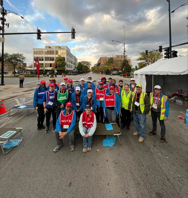 A group of Chicago Marathon volunteers at a road intersection with clear skies and urban buildings in the background.