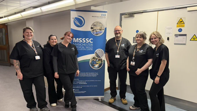 6 staff members at the MSSSC wearing black scrubs stood outside the cadaveric lab.