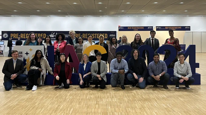Twenty-two people, including Team Space Enabled and Media Lab Director Dava Newman, pose with a large IAC 2024 sign.