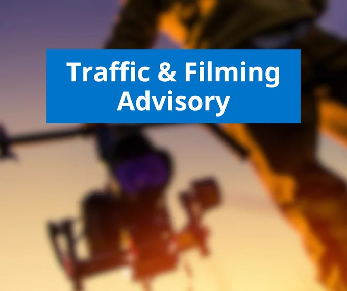 A blurred image of a camera in the background with text over top that reads "Traffic & Filming Advisory"