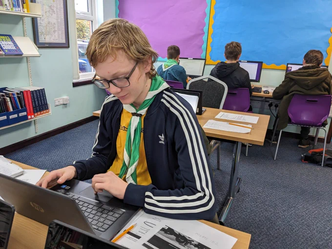 Scouts on laptops and computers in a library 