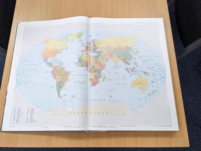 A large book opened to a double page spread of the world map