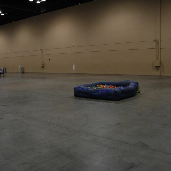 Picture of the Dash con ball pit. It's a small inflated kiddy pool with some plastic balls located in a huge empty convention hall.