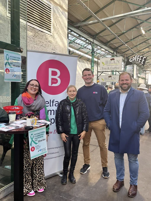 Ruth from RCSLT standing with 3 adults smiling in front of a pop up