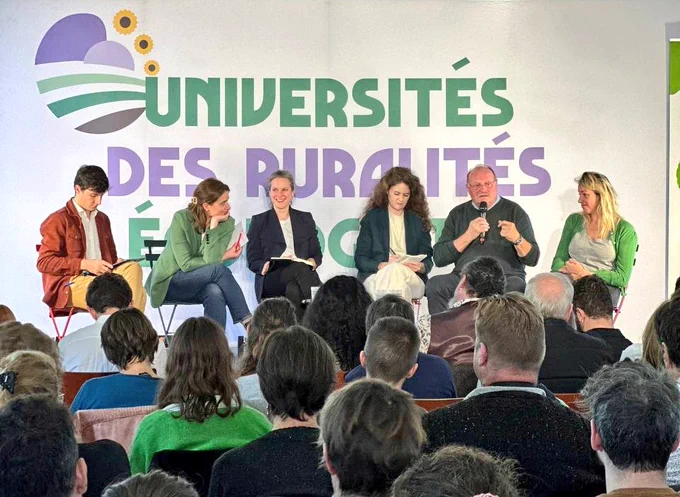 Cinq personnes assises devant une foule de personnes.