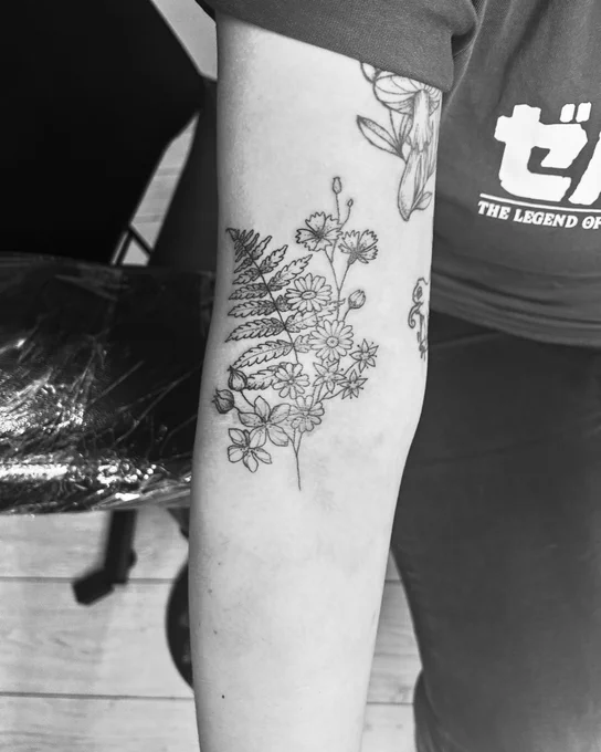A tattoo on Rosie’s arm, with a fern leaf and several small wildflowers