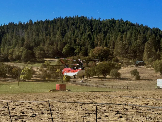 A helicopter hovers over the retardant tank on the Shoe Fire.