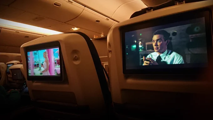 in-flight movies, view from my seat. just the screens are visible here, i'm watching openheimer on the right; another passenger (who wouldn't talk to me) is watching barbie on the left. the scenes are early into the respective movies, i tried to catch them at recognisable moments. both show the main characters, in super bright pink and almost entirely monochrome respectively