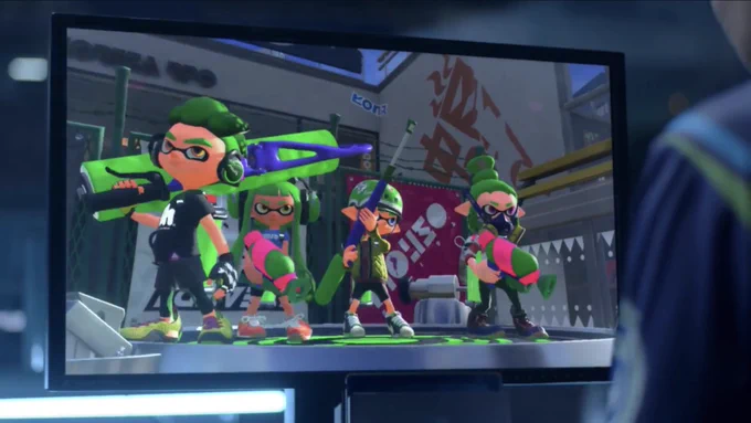 A team of four green Inklings stand on a spawn point as a player looks at the screen, from the Nintendo Switch reveal trailer