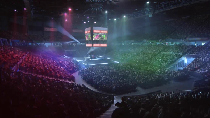 A giant arena crowd watches a Splatoon 2 eSports event, from the Nintendo Switch reveal trailer, with footage and the Nintendo logo shown on a jumbotron and the audience lit up in pink and green spotlights
