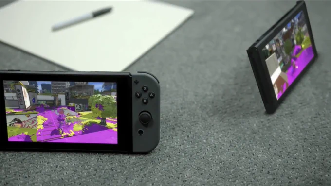 The first-ever shot of Splatoon 2 footage from the Nintendo Switch reveal trailer: two Switches in tabletop mode sit on the floor of a changing room next to a pad of paper and a pen