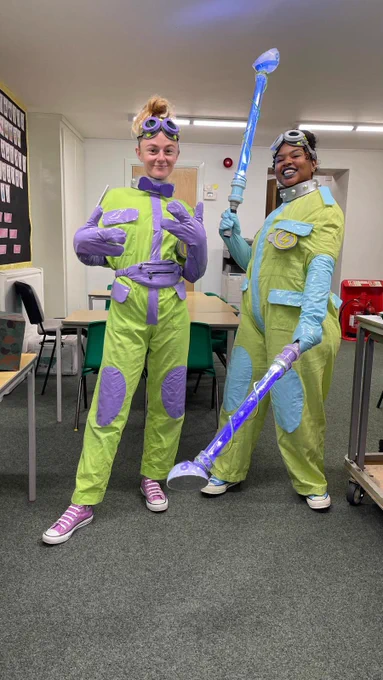 Clipboard and Scribble getting ready for action. Two performers in neon green jumpsuits, one with local detailing and the other with pale blue.