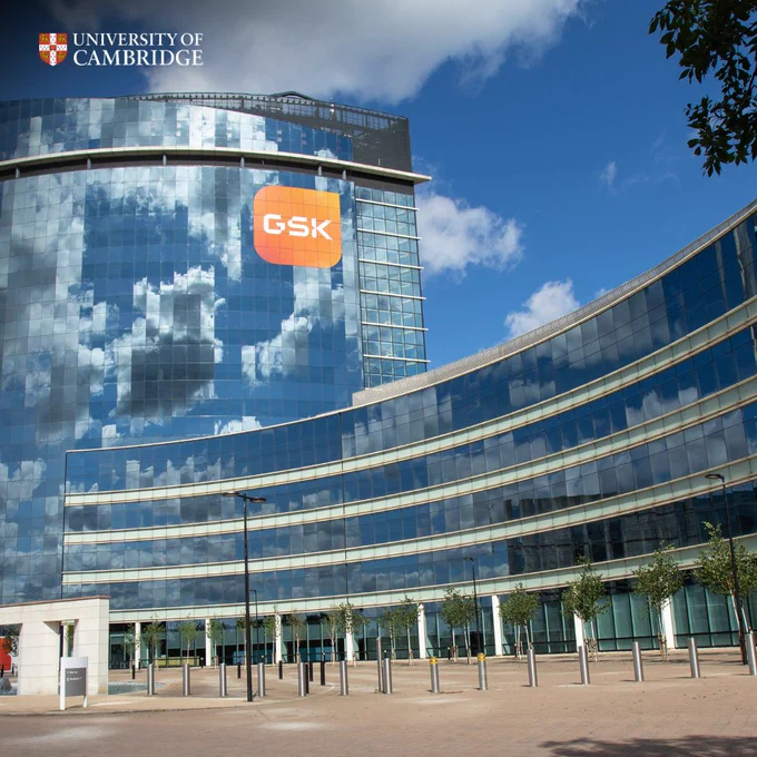 A modern glass building with the GlaxoSmithKline (GSK) logo, under a blue and partially cloudy sky.