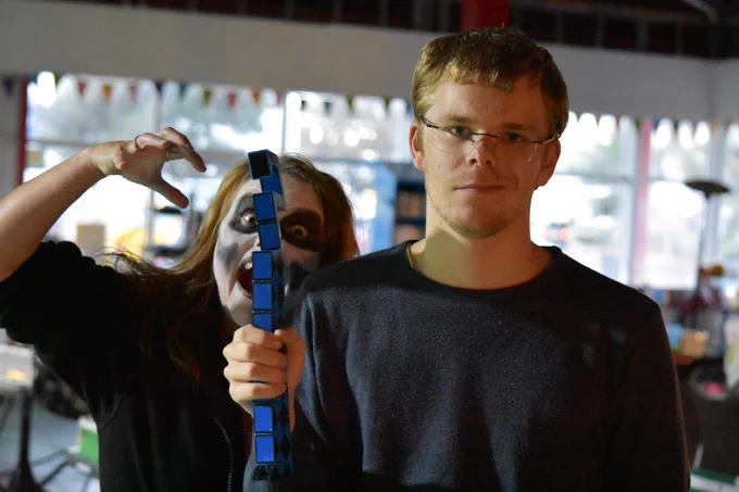 A player at last year's Halloween party posing for a photo unaware Loretta is pulling a scary pose behind them.