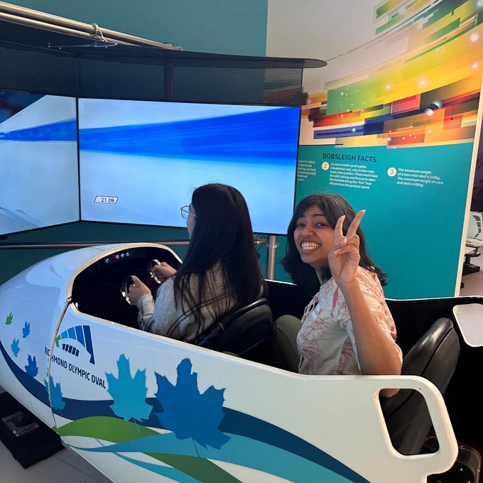 Khatidja and Didi riding the bobsleigh simulator at the Richmond Olympic Oval.