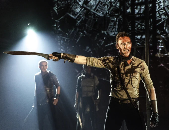 A man holds up a sword in anger as if ready to fight.