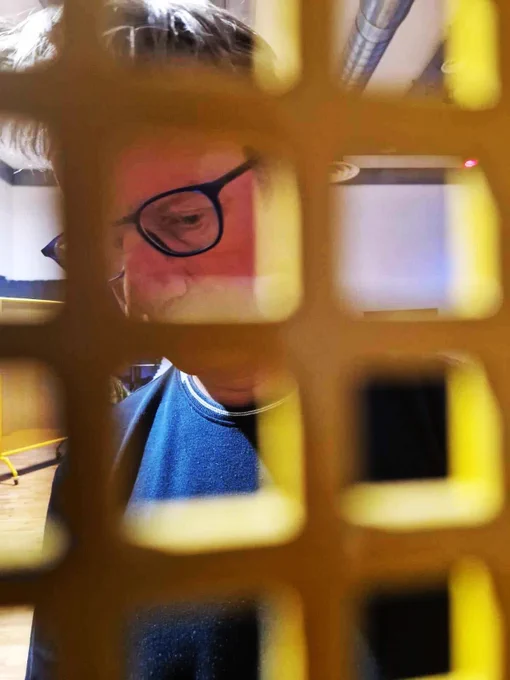 A male actor behind a mesh screen devising a task prototype for the show.