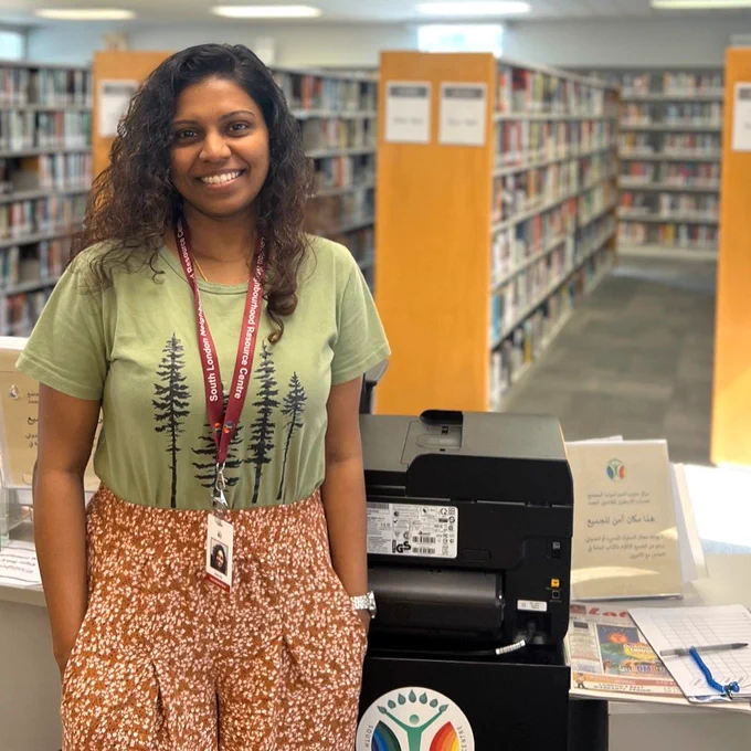LSP worker smiling and standing in front of her desk located in Jalna Branch Library.