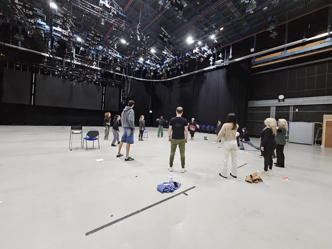 Artists standing in a circle in a huge studio space