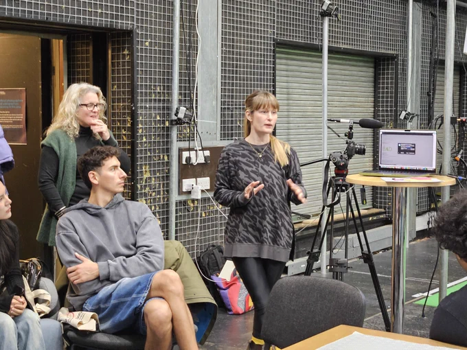A woman giving a talk to a group of artists