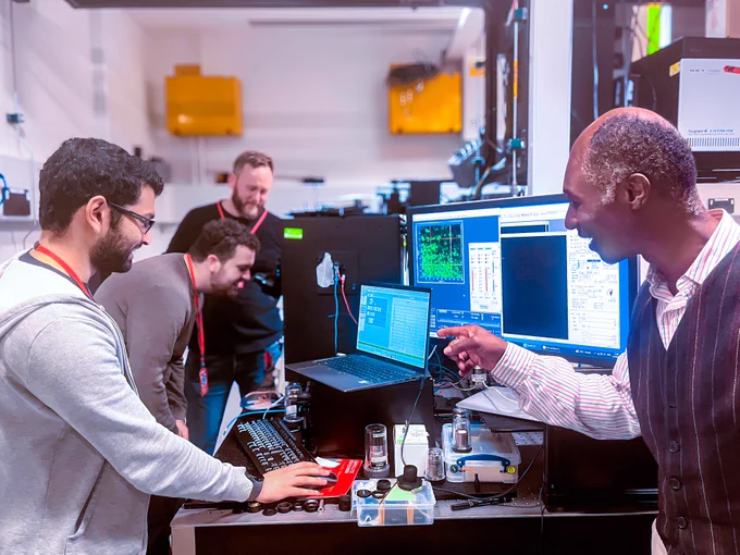 4 scientists work in the CLF Octopus Lab. Featured are microscopes and computer screens showing data from the experiment.