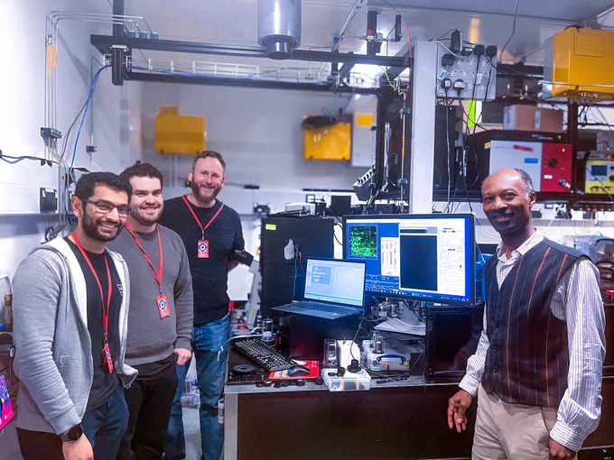 CLF and Liverpool scientists stand smiling in front of Octopus microscope