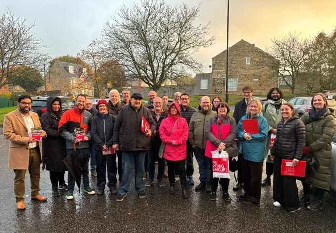 A large group of Labour Party campaigners standing outside in front of some houses