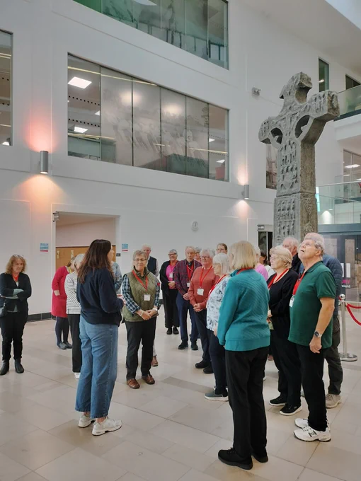 Photograph of a group of people standing in the PRONI atrium listening to a PRONI staff member providing a tour.
