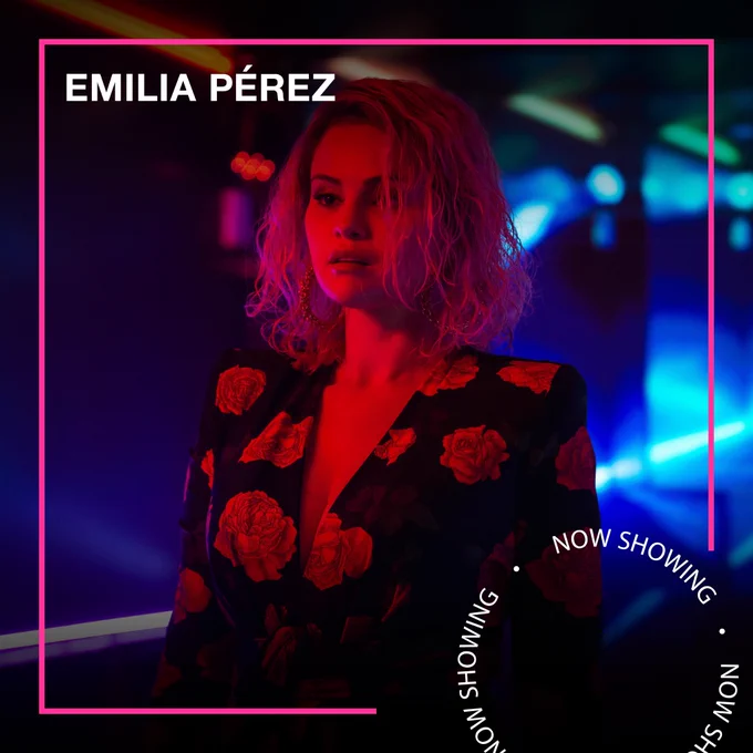 A blonde woman stands wearing a black dress. She is lit with red lighting. Text - Emilia Pérez, Now Showing