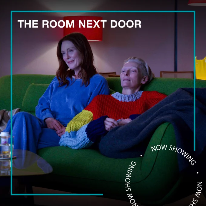 Two women sit on a green sofa together watching television. Text - The Room Next Door, Now Showing