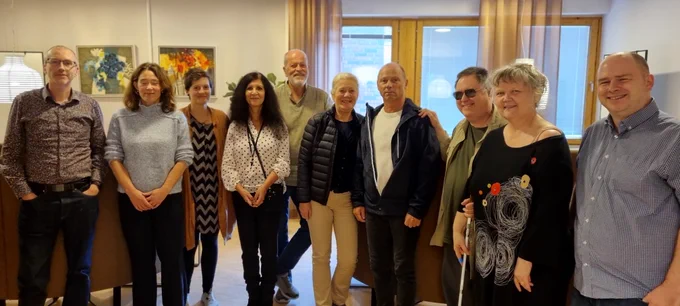A group of 10 people are standing in a row,all smiling.