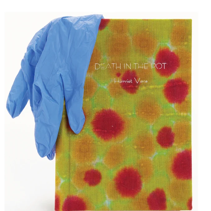 A clothbound book with green, blue, and red spots, which shows a blue latex glove resting on it. The book title reads “Death in the Pot / Harriet Vane”