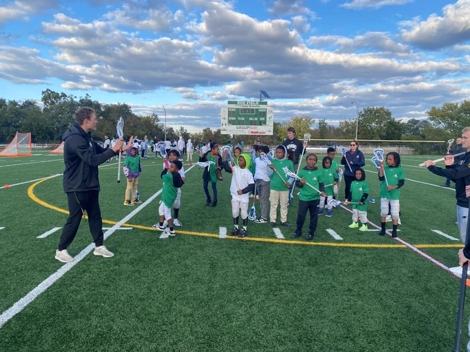 A college lacrosse player provides instruction to local youth. 