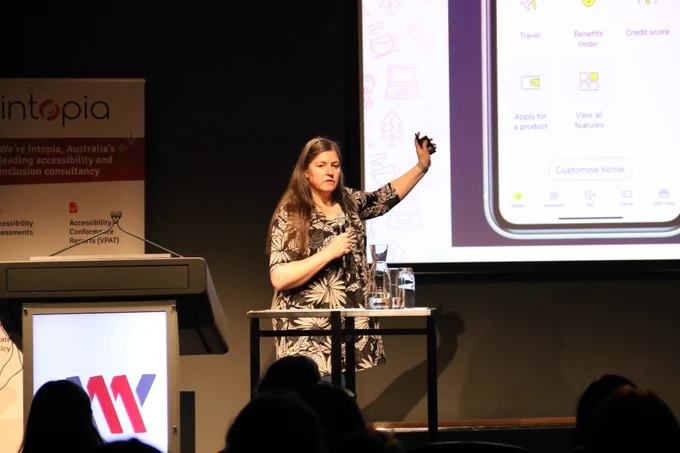 Allison speaking with one hand pointing to the screen. 