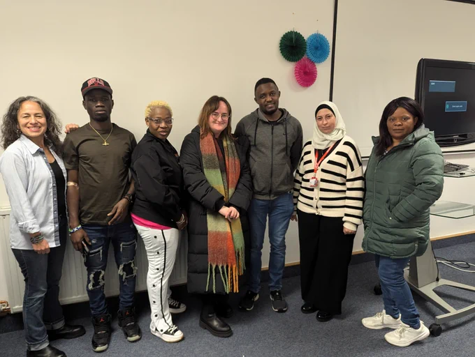 A group of people in a line smiling at the camera. The group is mostly made up of Voices Network ambassadors and at the centre is our Participation and Policy Officer.