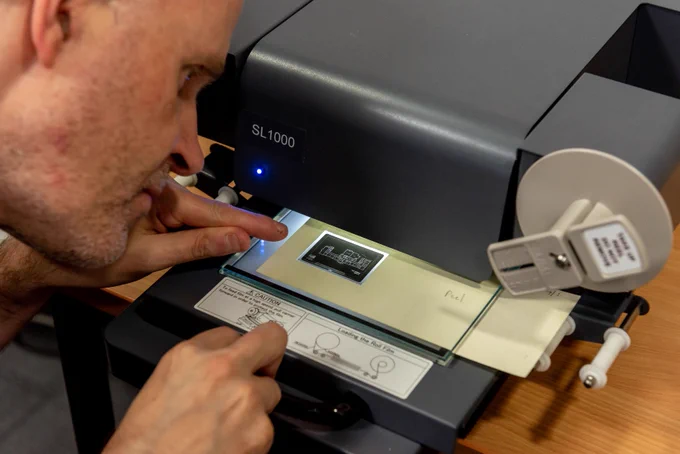 A person operates a microfiche machine.