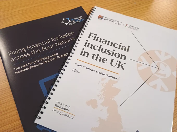 Two reports on a desk, titled 'Fixing Financial Exclusion across the Four Nations', and 'Financial inclusion in the UK'.